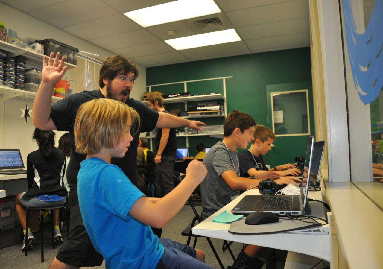 During an Empow Studios Summer STEM Camp, an Empow Studios camp counselor works with kids on their 3D modeling projects